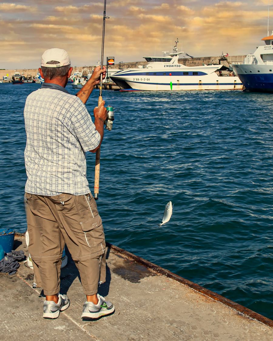 Angler reeling in a fish from a harbour pier